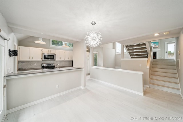 5743 E 72nd Pl Unit 11, Tulsa, OK 74136 - kitchen featuring stainless steel appliances, backsplash, a chandelier, pendant lighting, and a peninsula