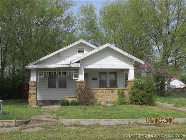 804 N Oklahoma St, Okmulgee, OK 74447 - bungalow featuring covered porch, a front yard, and stone siding