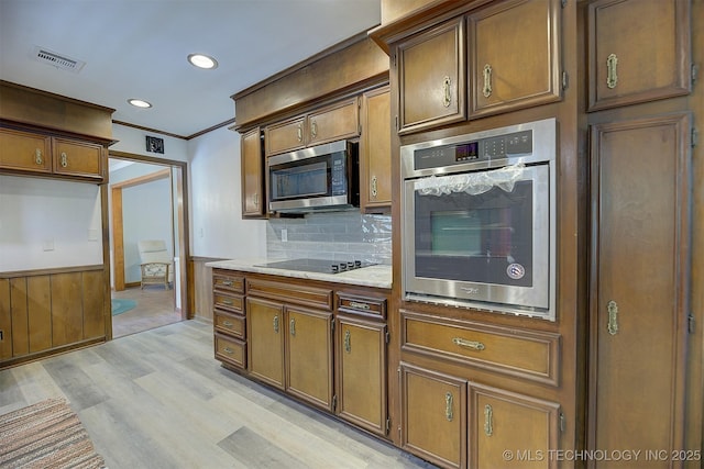 583 S Joplin Ave, Tulsa, OK 74112 - kitchen with appliances with stainless steel finishes, light wood finished floors, decorative backsplash, recessed lighting, and brown cabinetry