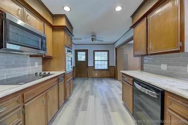 583 S Joplin Ave, Tulsa, OK 74112 - kitchen featuring black appliances, light wood-style floors, brown cabinetry, ceiling fan, and wainscoting