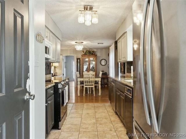 31990 S 624th Pl Unit 48, Grove, OK 74344 - kitchen featuring freestanding refrigerator, black range with electric cooktop, a chandelier, white microwave, and light tile patterned floors