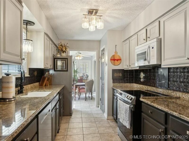 31990 S 624th Pl Unit 48, Grove, OK 74344 - kitchen with appliances with stainless steel finishes, a textured ceiling, a chandelier, light tile patterned floors, and a ceiling fan