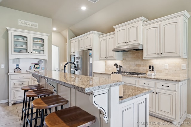 5814 130th W Ave, Sand Springs, OK 74063 - kitchen with appliances with stainless steel finishes, under cabinet range hood, vaulted ceiling, tasteful backsplash, and a breakfast bar