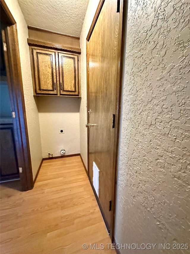204 E 24th Ct, Owasso, OK 74055 - laundry area featuring cabinet space, light wood-type flooring, a textured ceiling, and hookup for an electric dryer