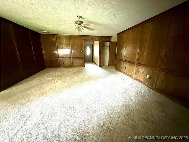 204 E 24th Ct, Owasso, OK 74055 - spare room with a ceiling fan, a decorative wall, wood walls, light carpet, and a textured ceiling