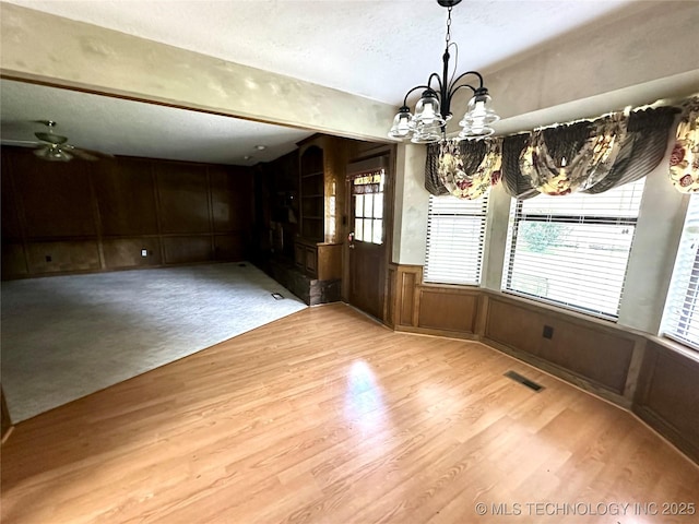 204 E 24th Ct, Owasso, OK 74055 - unfurnished dining area featuring a chandelier, light wood-style floors, plenty of natural light, a ceiling fan, and wainscoting