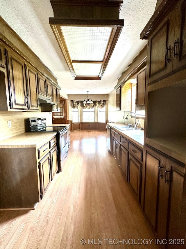 204 E 24th Ct, Owasso, OK 74055 - kitchen with stainless steel appliances, a chandelier, light wood finished floors, under cabinet range hood, and light countertops