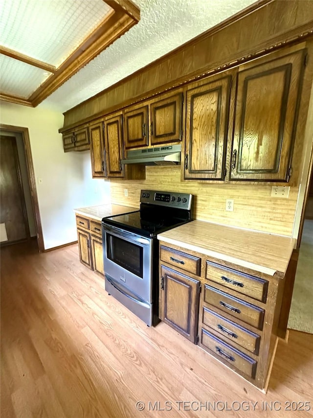 204 E 24th Ct, Owasso, OK 74055 - kitchen featuring stainless steel range with electric stovetop, under cabinet range hood, light countertops, light wood-type flooring, and crown molding