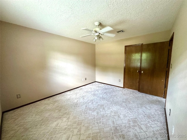 204 E 24th Ct, Owasso, OK 74055 - unfurnished bedroom with a closet, a ceiling fan, a textured ceiling, and brick patterned floors