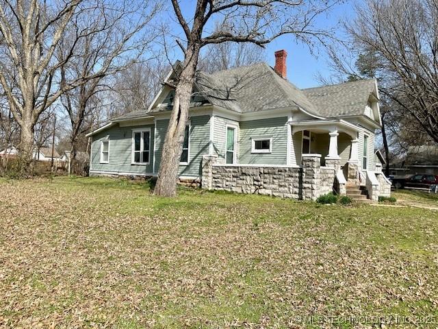 349 S Foreman St, Vinita, OK 74301 - view of side of property featuring a chimney, a yard, covered porch, and roof with shingles