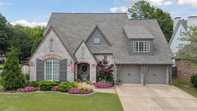 5117 E 92nd St, Tulsa, OK 74137 - view of front of home with stone siding, a front yard, concrete driveway, and a shingled roof