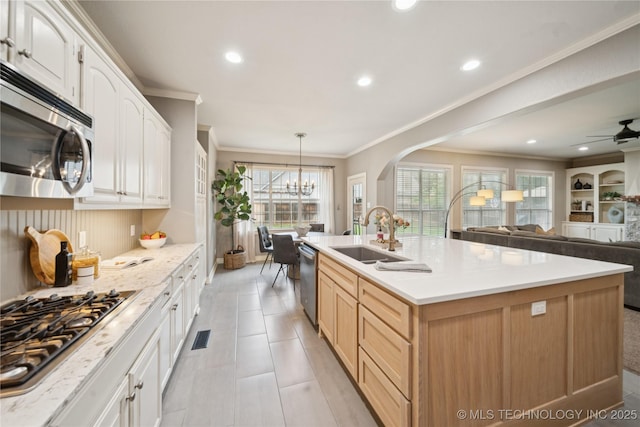 5117 E 92nd St, Tulsa, OK 74137 - kitchen with appliances with stainless steel finishes, crown molding, a chandelier, open floor plan, and a center island with sink