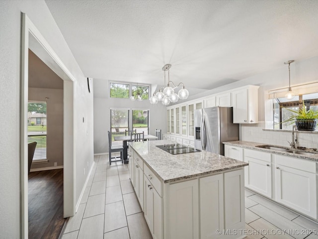 5607 E 76th St, Tulsa, OK 74136 - kitchen with stainless steel refrigerator with ice dispenser, black electric cooktop, a kitchen island, and white cabinetry