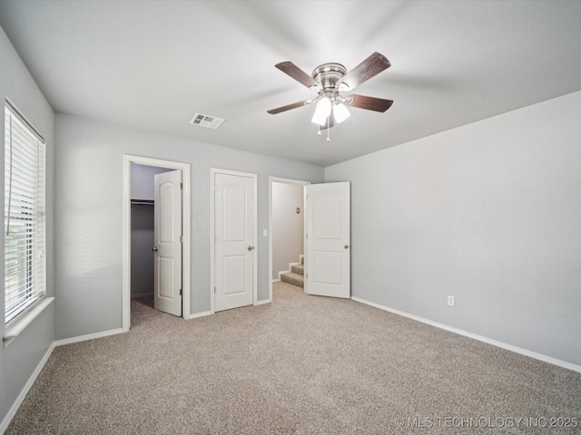 5607 E 76th St, Tulsa, OK 74136 - unfurnished bedroom with multiple windows, carpet flooring, a walk in closet, and ceiling fan