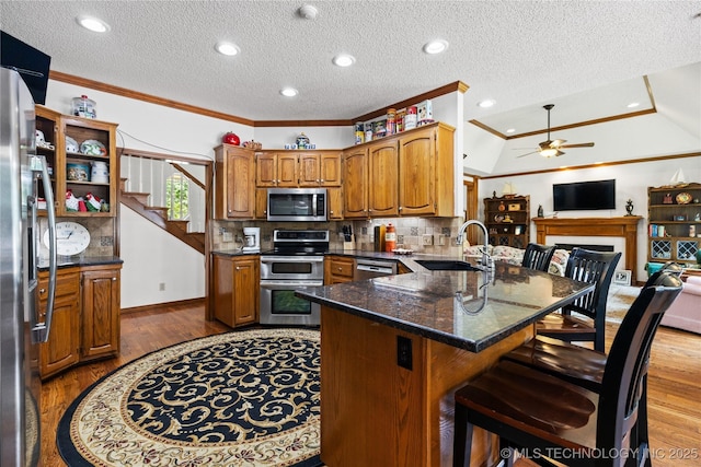 501 W 35th Pl, Sand Springs, OK 74063 - kitchen with appliances with stainless steel finishes, a peninsula, ceiling fan, a kitchen breakfast bar, and wood finished floors