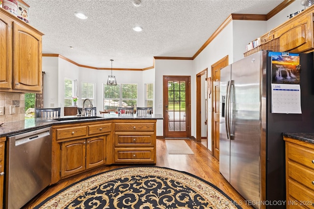 501 W 35th Pl, Sand Springs, OK 74063 - kitchen featuring appliances with stainless steel finishes, light wood-style flooring, a peninsula, a textured ceiling, and dark countertops