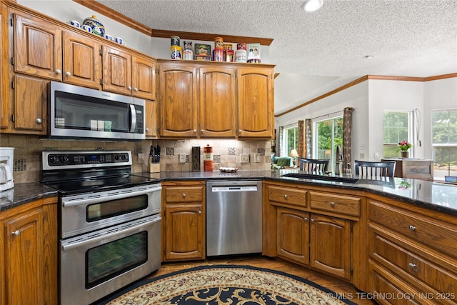 501 W 35th Pl, Sand Springs, OK 74063 - kitchen featuring appliances with stainless steel finishes, crown molding, a textured ceiling, dark countertops, and brown cabinetry