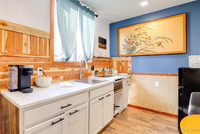 62141 E 313th Rd Unit 3, Grove, OK 74344 - kitchen with freestanding refrigerator, wainscoting, wood walls, white cabinetry, and light wood-style flooring