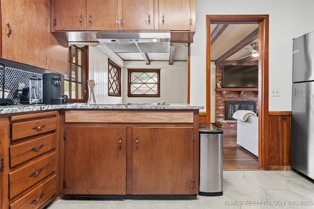 5225 S Toledo Ave, Tulsa, OK 74135 - kitchen featuring freestanding refrigerator, a brick fireplace, electric stovetop, a ceiling fan, and brown cabinets
