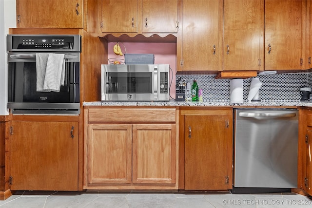 5225 S Toledo Ave, Tulsa, OK 74135 - kitchen with stainless steel appliances, tasteful backsplash, brown cabinetry, and light countertops