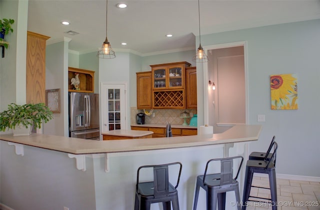 14230 S Urbana Ave, Bixby, OK 74008 - kitchen with stainless steel fridge with ice dispenser, brown cabinetry, tasteful backsplash, a breakfast bar area, and light countertops