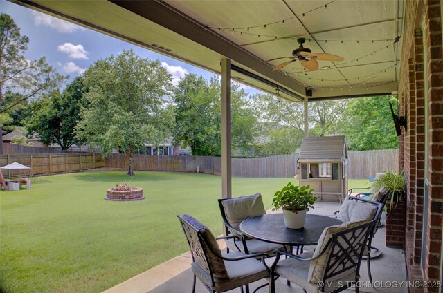 14230 S Urbana Ave, Bixby, OK 74008 - fenced backyard featuring ceiling fan, an outdoor structure, an outdoor fire pit, a patio, and outdoor dining space