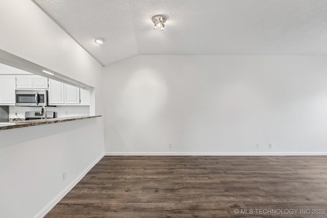 8316 E 81st Pl, Tulsa, OK 74133 - kitchen featuring appliances with stainless steel finishes, vaulted ceiling, white cabinetry, dark wood-style floors, and a textured ceiling