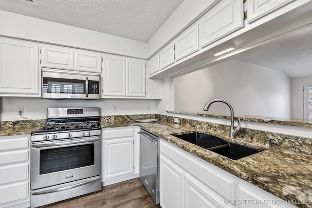 8316 E 81st Pl, Tulsa, OK 74133 - kitchen with appliances with stainless steel finishes, a textured ceiling, dark stone counters, white cabinets, and dark wood finished floors
