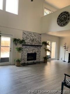 4822 S Quaker Ave, Tulsa, OK 74105 - unfurnished living room featuring a high ceiling, healthy amount of natural light, wood finished floors, and a fireplace