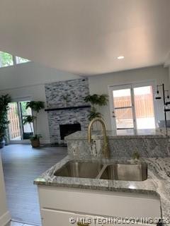 4822 S Quaker Ave, Tulsa, OK 74105 - kitchen view of a fireplace, light stone counters, and wood finished floors