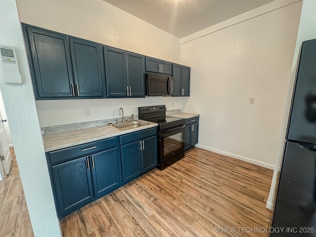 916 Coy Ave, Tahlequah, OK 74464 - kitchen featuring black appliances, light wood-type flooring, light countertops, blue cabinetry, and a textured wall
