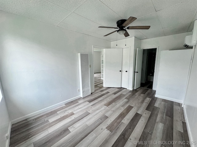 916 Coy Ave, Tahlequah, OK 74464 - unfurnished bedroom featuring a heating unit, wood finished floors, a wall mounted air conditioner, a closet, and a drop ceiling