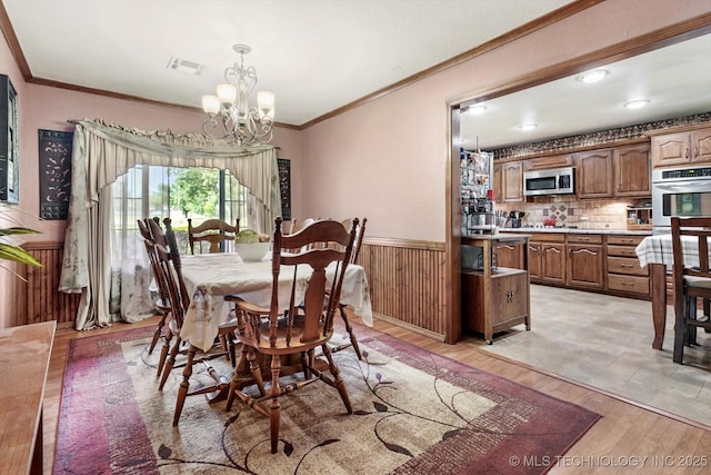 4152 W Oak St, Skiatook, OK 74070 - dining area featuring ornamental molding, a chandelier, wainscoting, light wood-style flooring, and wood walls
