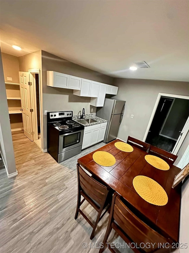 1026 N Utica Ave, Tulsa, OK 74110 - kitchen featuring appliances with stainless steel finishes, white cabinets, and light wood-type flooring