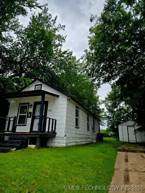 1026 N Utica Ave, Tulsa, OK 74110 - view of side of home with a storage unit, a yard, and a porch