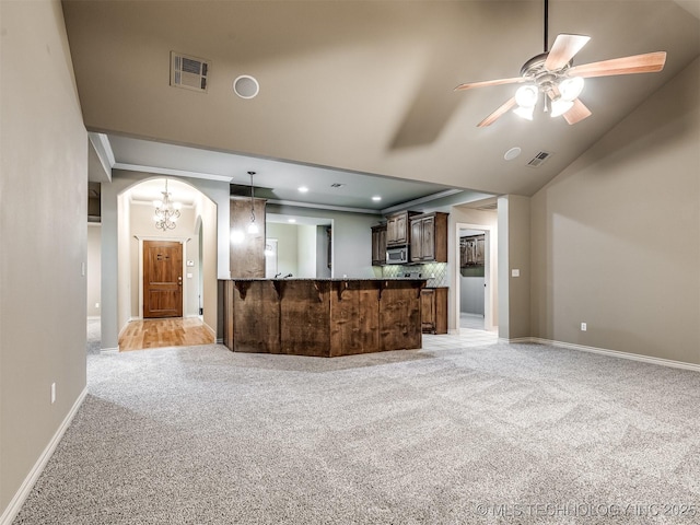 4667 E 144th Pl S, Bixby, OK 74008 - kitchen featuring light colored carpet, stainless steel microwave, arched walkways, ceiling fan, and hanging light fixtures
