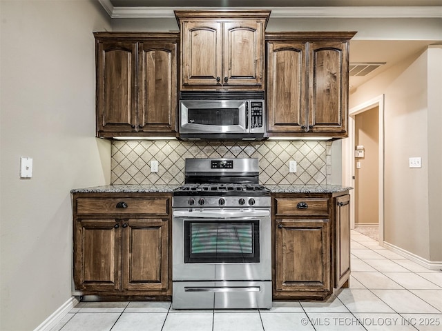 4667 E 144th Pl S, Bixby, OK 74008 - kitchen featuring stainless steel appliances, stone counters, backsplash, light tile patterned floors, and dark brown cabinetry