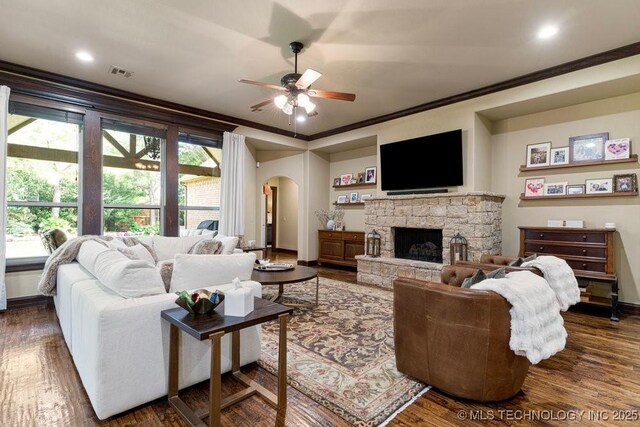 2015 W 109th St, Jenks, OK 74037 - living room featuring arched walkways, crown molding, a ceiling fan, dark wood-style floors, and a fireplace