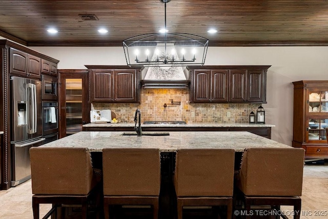 2015 W 109th St, Jenks, OK 74037 - kitchen featuring stainless steel appliances, ventilation hood, dark brown cabinetry, light stone countertops, and a chandelier