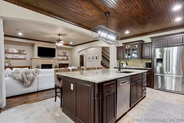 2015 W 109th St, Jenks, OK 74037 - kitchen with appliances with stainless steel finishes, arched walkways, a ceiling fan, dark brown cabinets, and stone tile flooring