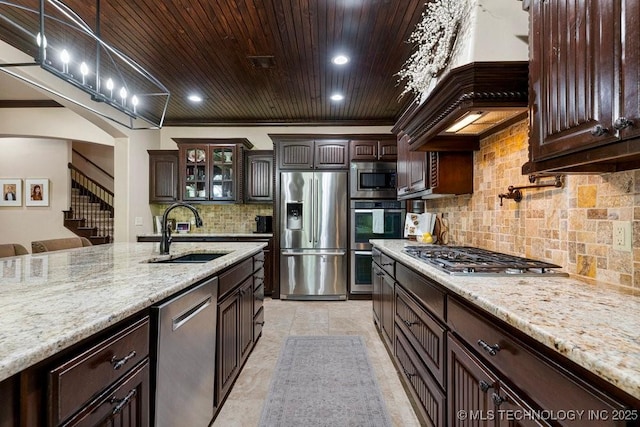 2015 W 109th St, Jenks, OK 74037 - kitchen featuring appliances with stainless steel finishes, custom range hood, dark brown cabinets, glass insert cabinets, and wood ceiling