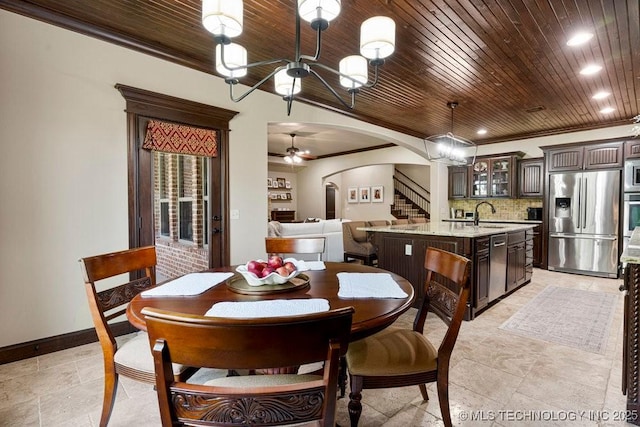 2015 W 109th St, Jenks, OK 74037 - dining room featuring arched walkways, stairs, a ceiling fan, a chandelier, and stone tile floors