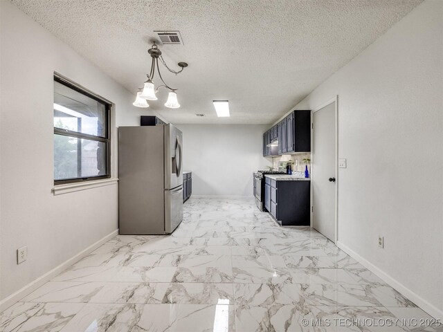 314 N Tallchief St, Skiatook, OK 74070 - kitchen with stainless steel appliances, dark cabinetry, light countertops, a textured ceiling, and light marble finish floors