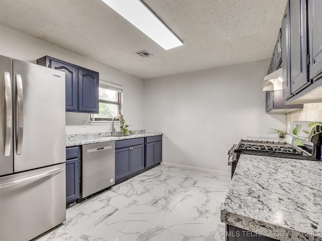 314 N Tallchief St, Skiatook, OK 74070 - kitchen with appliances with stainless steel finishes, blue cabinets, under cabinet range hood, a textured ceiling, and light marble finish flooring