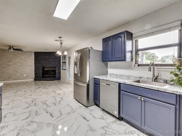 314 N Tallchief St, Skiatook, OK 74070 - kitchen with stainless steel appliances, blue cabinets, a textured ceiling, a stone fireplace, and open floor plan