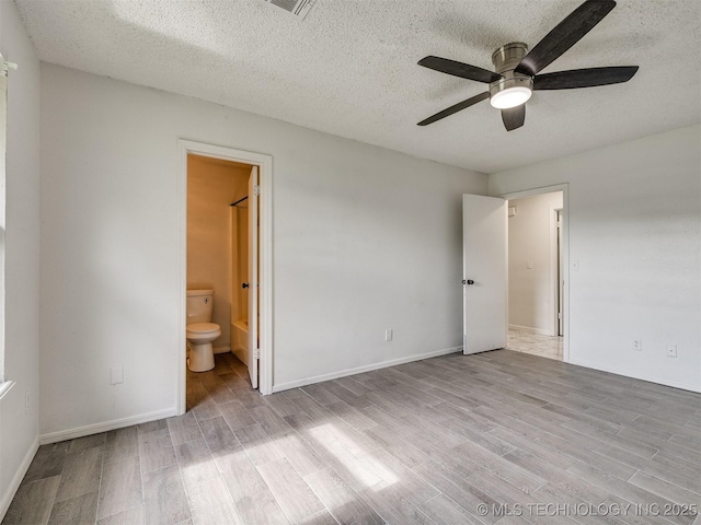 314 N Tallchief St, Skiatook, OK 74070 - unfurnished bedroom featuring wood finished floors, a textured ceiling, ensuite bathroom, and ceiling fan
