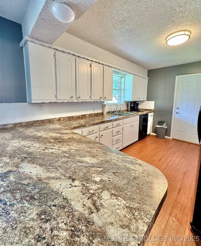 115842 S 4196, Checotah, OK 74426 - kitchen with a textured ceiling, dishwasher, light wood-style floors, white cabinets, and dark countertops