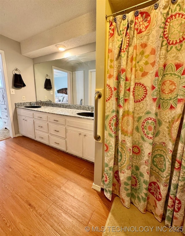 115842 S 4196, Checotah, OK 74426 - bathroom featuring wood finished floors, double vanity, a textured ceiling, and a shower with curtain