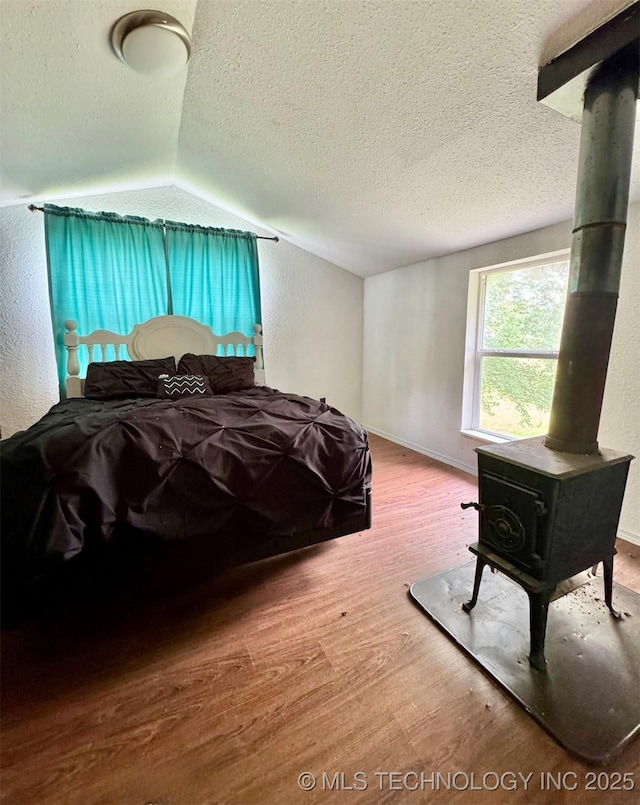 115842 S 4196, Checotah, OK 74426 - bedroom with a wood stove, wood finished floors, a textured ceiling, and lofted ceiling
