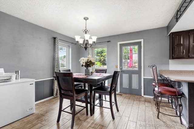 2605 W Atlanta Ct, Broken Arrow, OK 74012 - dining space with a chandelier, light wood-style flooring, a textured ceiling, and wainscoting